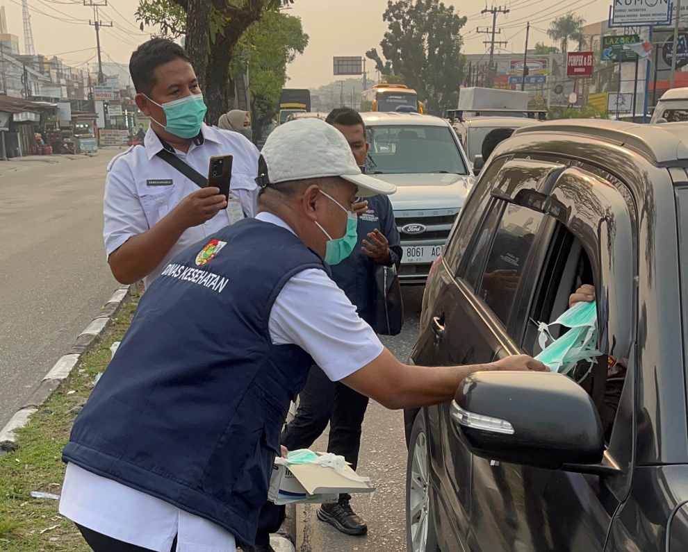 : Sekretaris Dinas Kesehatan Kota Pekanbaru, Dedy Sambudi turun ke jalanan memberikan masker ke pengendara. - Foto: Mc.Pekanbaru