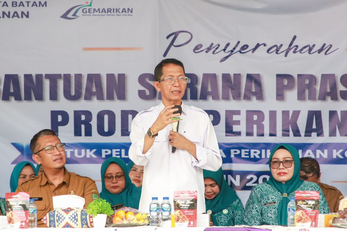 : Wali kota Batam, Amsakar Achmad, didampingi Ketua TP-PKK Batam, Erlita Amsakar, dan Kepala Dinas Perikanan Kota Batam, Yudi Atmajianto, menyampaikan, sambutan saat penyerahan bantuan sarana dan prasarana kepada kelompok pengolah dan pemasaran hasil perikanan di Sagulung, Senin (14/9/2026). HUMAS DISKOMINFO BATAM / NOVRI MULYADI