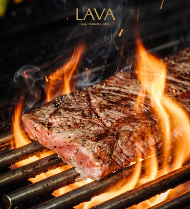 Koki Lava Gastrobar memasak steak di atas pemanggang dengan api terbuka