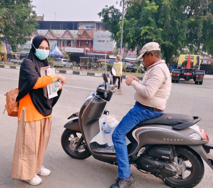 : Seorang ASN Dinas Kesehatan Siak membagikan Masker gratis kepada pengendara motor di Kota Siak, Sabtu (5/9/2026)/ (Agi/MC Siak).