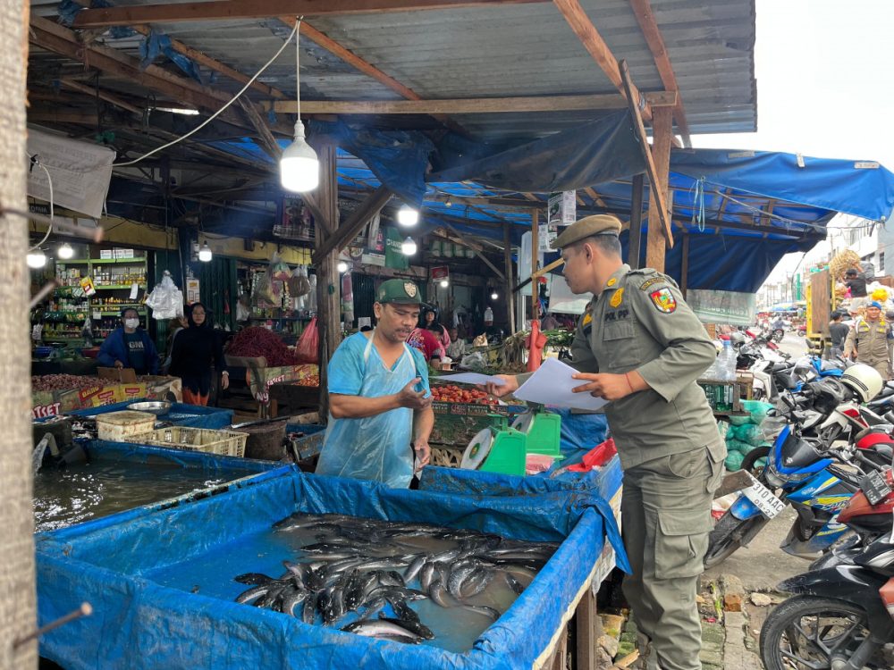 : Petugas Dinas Perindustrian dan Perdagangan (Disperindag) Kota Pekanbaru dan Satuan Polisi Pamong Praja (Satpol PP) Kota Pekanbaru menyerahkan, surat pemberitahuan kepada pedagang agar mengosongkan Jalan Teratai, Kota Pekanbaru.- Foto: Mc.Pekanbaru