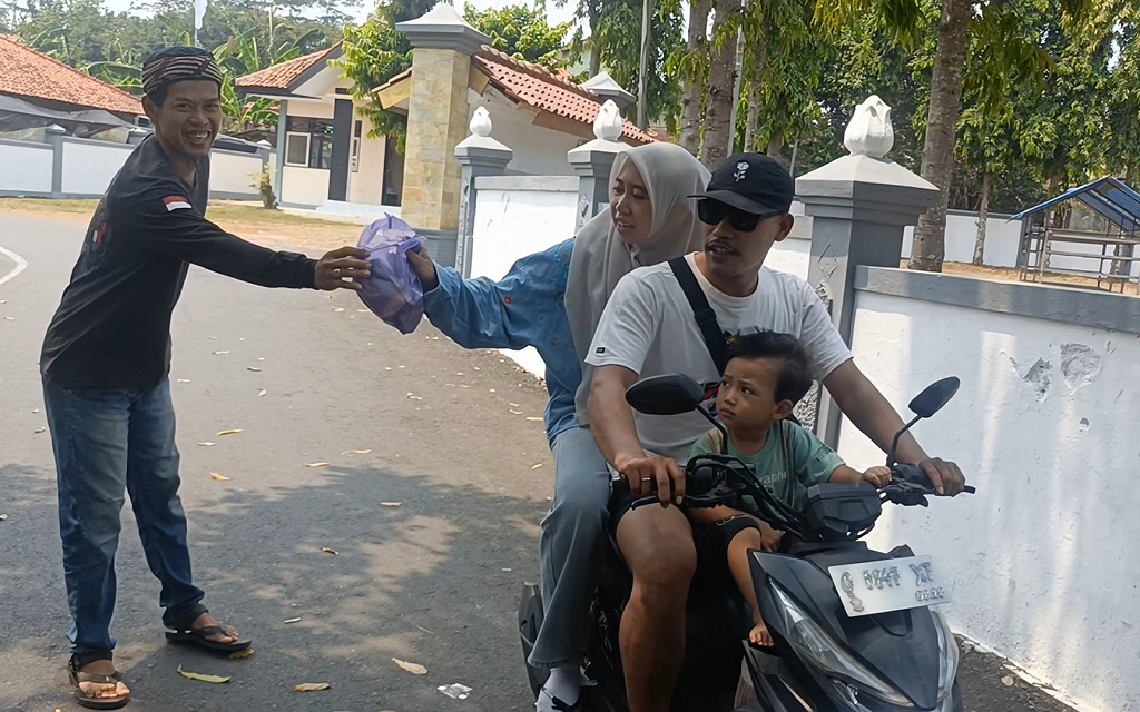 : alah satu Pemuda Makam Pahlawan Kadilangu (kiri), membagikan sayuran kepada pengguna jalan dalam rangka Memperingati Hari Kesaktian Pancasila di Komplek Makam Pahlawan Kadilangu, Kabupaten Batang.